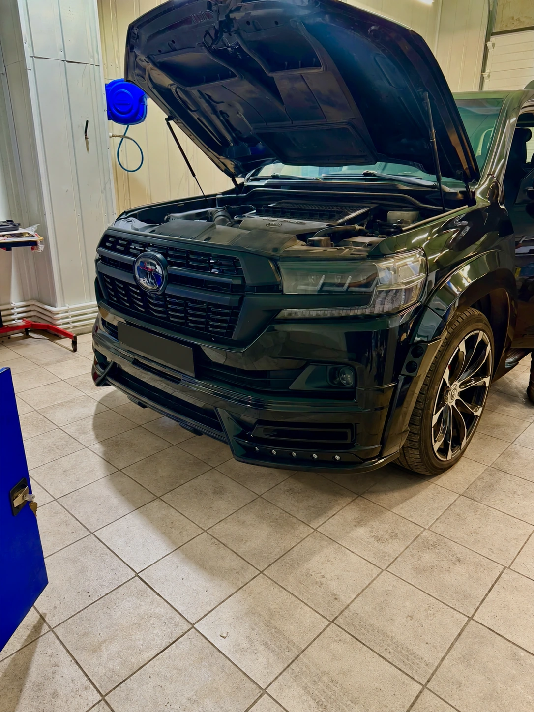 Toyota Land Cruiser 200 с открытым капотом в ремонтном боксе